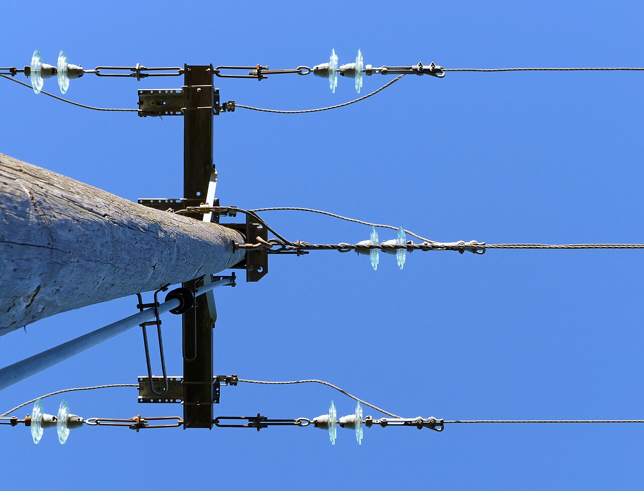 The top of a power-line pole with cross-arms and conductors — the kind of asset detected automatically.